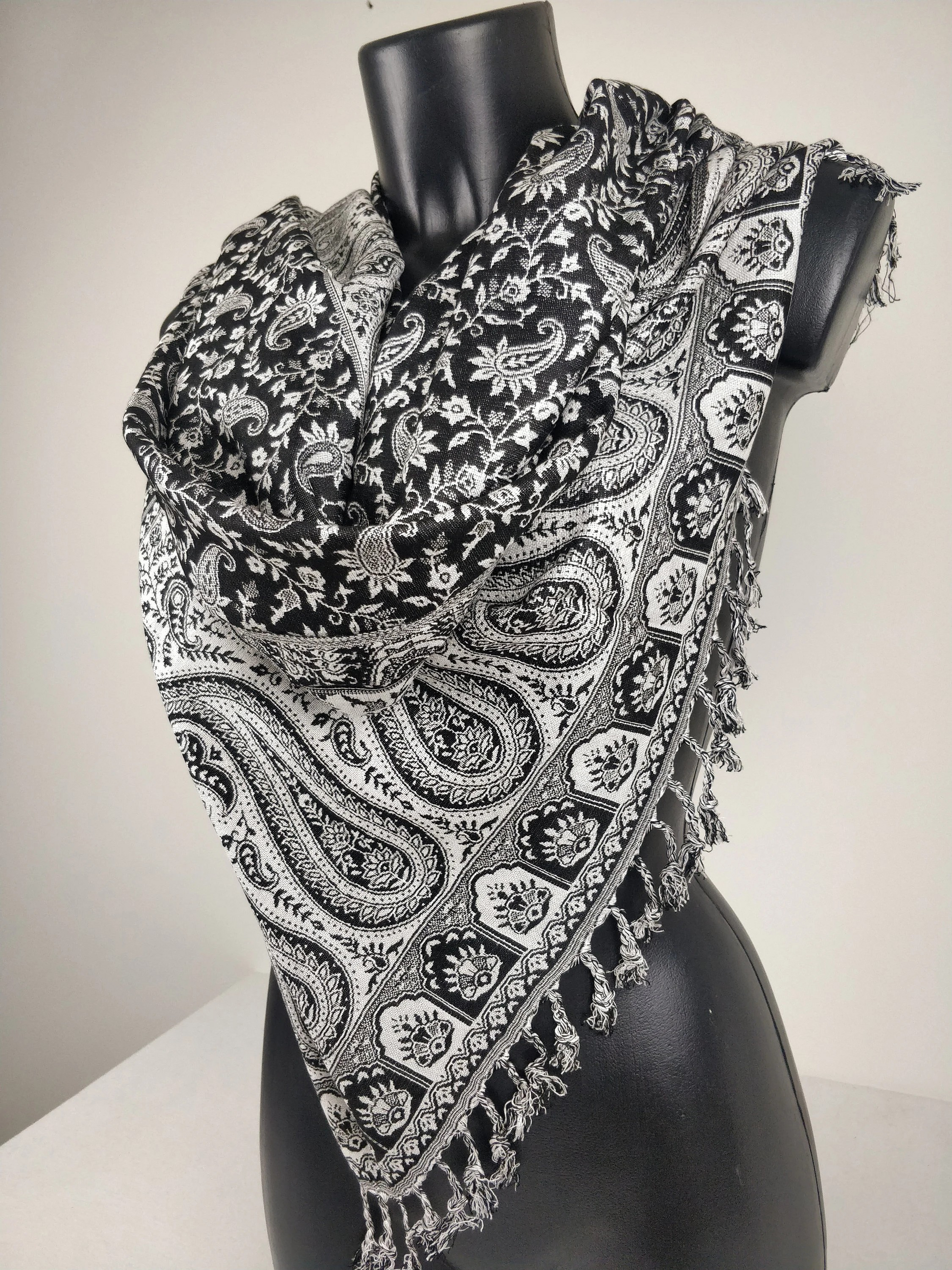 Écharpe pashmina élégante avec motifs paisley noirs et blancs, fabriquée en viscose réversible.